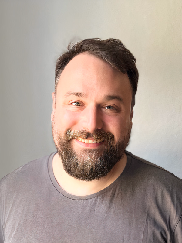 Der Therapeut hat ein freundliches Lächeln, eine offene Körperhaltung und einen einladenden Ausdruck.